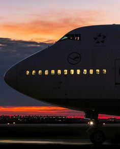 an airplane is sitting on the runway at night with its lights on and it's windows lit up