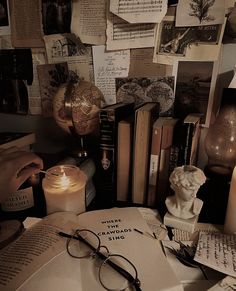 a table topped with books and glasses on top of a desk next to a candle