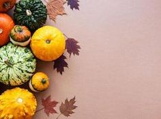 various fruits and vegetables are arranged in a circle on a table with autumn leaves around them