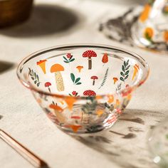 a glass bowl sitting on top of a table next to utensils and spoons