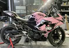 a pink and black motorcycle parked on top of a metal grate in a garage