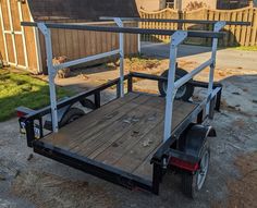 the trailer is parked on the side of the road in front of a fenced yard