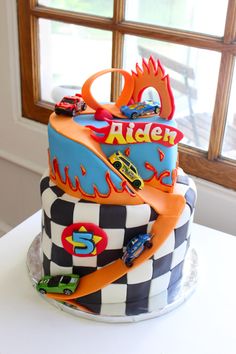 a birthday cake is decorated with cars and checkered paper