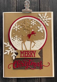 a christmas card with a deer and snowflakes on it, in front of a wooden background