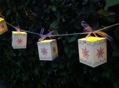 some lights that are hanging from a line with paper bags attached to the string in front of them