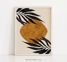 an art print with black and gold leaves on it, in front of a white wall