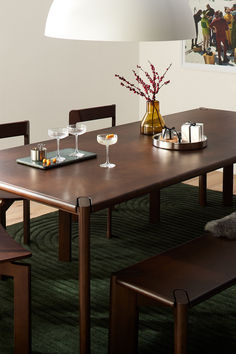 a dining room table with two chairs and a vase filled with flowers next to it