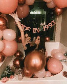 two women standing in front of a table with balloons