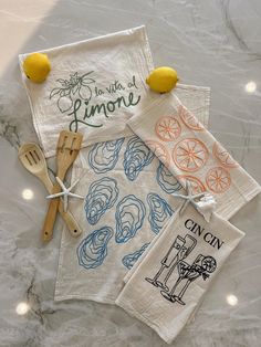 three tea towels with lemons on them sitting next to some kitchen utensils