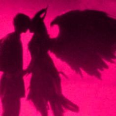 the shadow of two people standing next to each other in front of a pink background