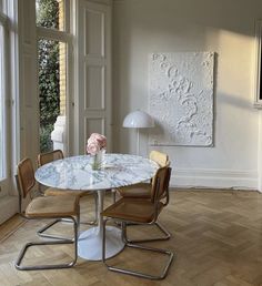 a table with chairs and a vase on top of it in front of a window