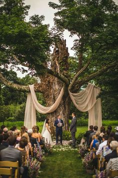 a bride and groom standing at the end of their wedding ceremony under an old tree