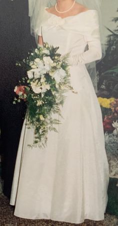 an old photo of a bride and groom posing for a wedding photograph in front of a floral wall