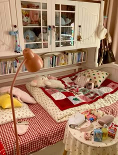 a room with two beds, a table and some bookshelves on the wall