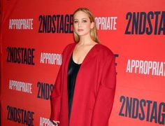 a woman standing in front of a red wall with the words zndstage on it