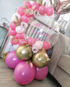 balloon arch with pink, gold and white balloons in the shape of butterflies on it