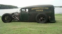 an old car is parked on the grass by the water in front of some trees