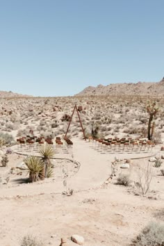 an outdoor wedding setup in the desert with chairs and tables set up on each side