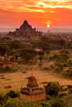 the sun is setting over temples in an open field