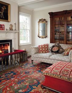 a living room filled with furniture and a fire place next to a bookcase full of books