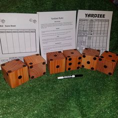 several wooden dices sitting on top of green grass next to two sheets of paper