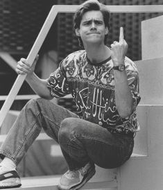 black and white photograph of a young man sitting on steps with his hand up in the air