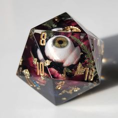 a close up of a dice with an eye on it and gold trimmings