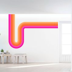 a white room with an orange and pink pipe on the wall next to a table