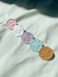 four different colored buttons sitting on top of a white sheet