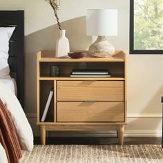 a bedroom with a bed, nightstand and lamp on top of the night stand in front of the window