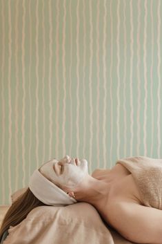 a woman laying on top of a bed wearing a white mask