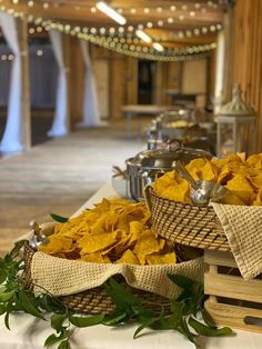 two baskets filled with chips sitting on top of a table next to other food items