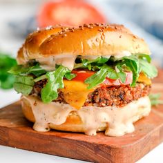 a cheeseburger with lettuce and tomatoes on a cutting board, ready to be eaten