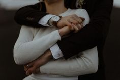 a woman with her arms crossed wearing a white sweater and black jacket