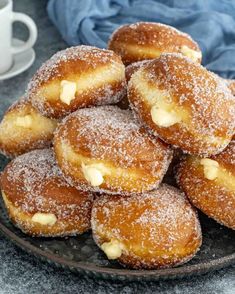 powdered sugar covered doughnuts on a plate next to a cup of coffee