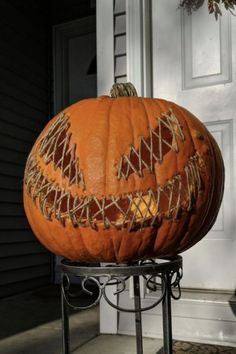 a large pumpkin sitting on top of a metal stand in front of a door with string wrapped around it