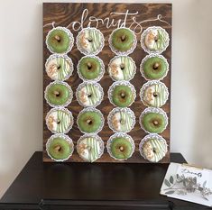 a wooden sign that says donuts on it with green frosting and sprinkles