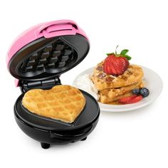 waffle maker with heart shaped waffles and strawberries on the plate next to it