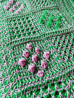 green and pink crocheted table cloth with flowers on it