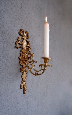 a candle that is on the wall next to a candelabra with leaves