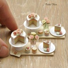 miniature cakes and cupcakes sitting on small trays with fingers pointing at them