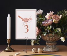 a vase with flowers and candles on a table next to a card that says 3