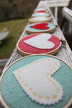 four hand embroidered hoops on a wooden table with grass and trees in the background