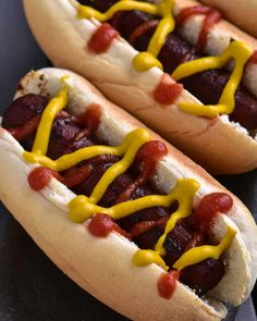 two hotdogs with mustard and ketchup on them sitting next to each other