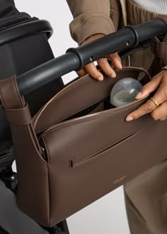 a person holding a brown purse with a computer mouse in it