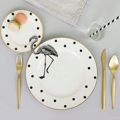 a plate with a flamingo design on it next to a fork, knife and an egg