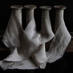 three white vases sitting next to each other on top of a wooden table covered in cloth