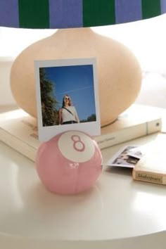 a pink ball sitting on top of a table next to a lamp and photo frame