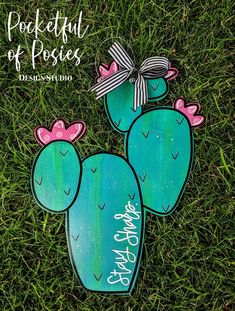 two painted cactuses sitting in the grass with a bow on their heads and words that read pocketful of posies