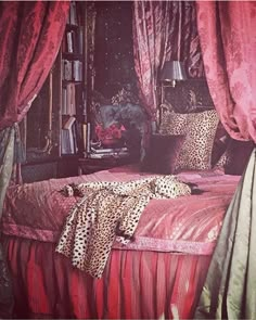 a leopard print bed spread and pillows in a room with pink curtains on the windowsill